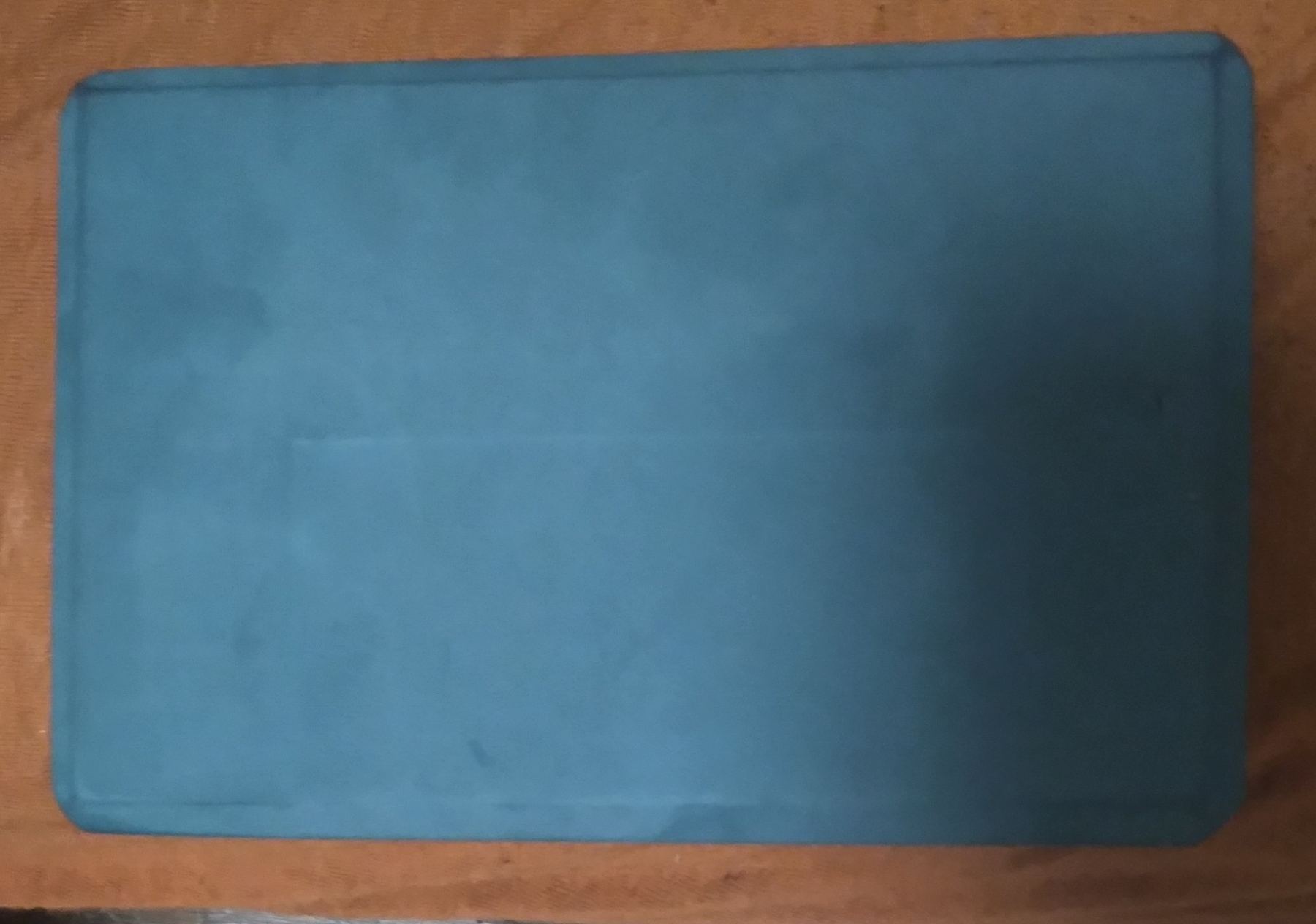 A rolled yoga mat resting on a wooden surface, representing Yogasya's Relaxation Products category